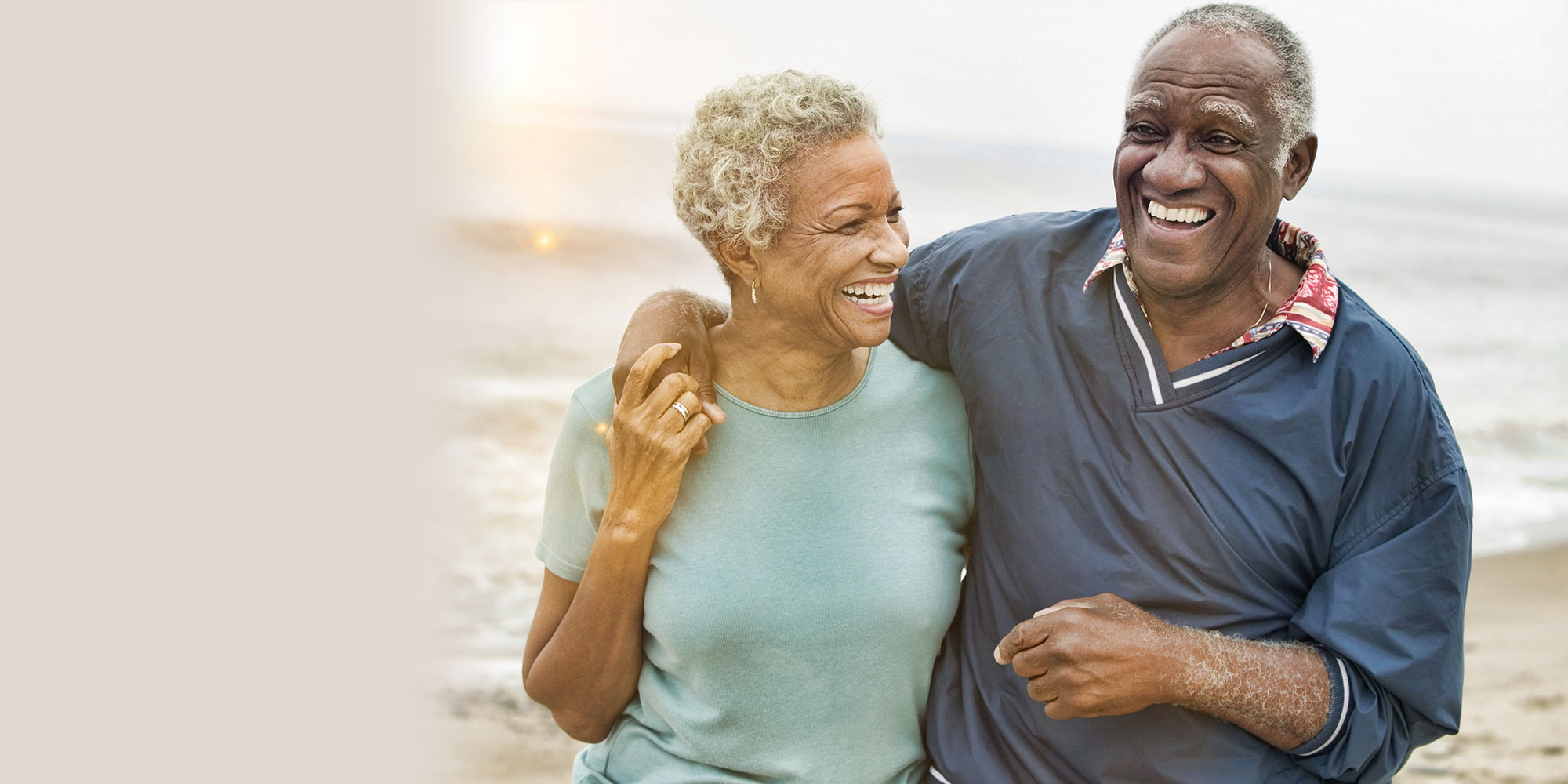 old couple smiling walking down the beach