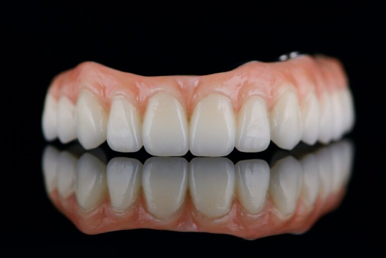 Close-up image of a dentist smiling with a patient, showcasing their new full mouth implants. The patient is also smiling confidently. No text on the image.