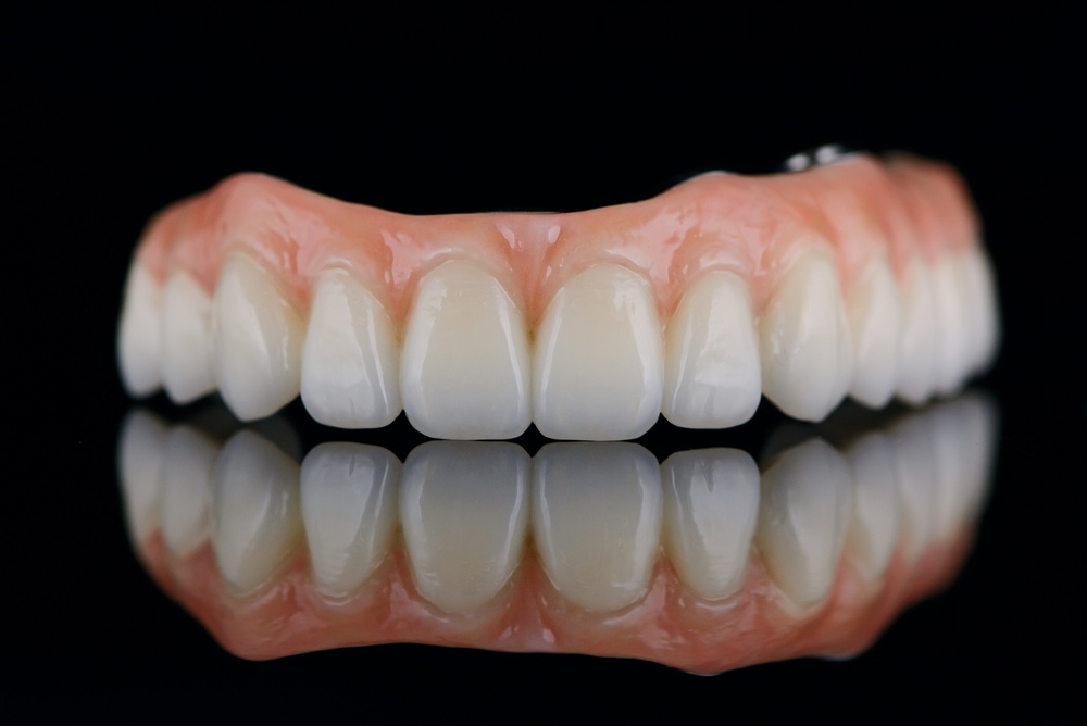 Close-up image of a dentist smiling with a patient, showcasing their new full mouth implants. The patient is also smiling confidently. No text on the image.